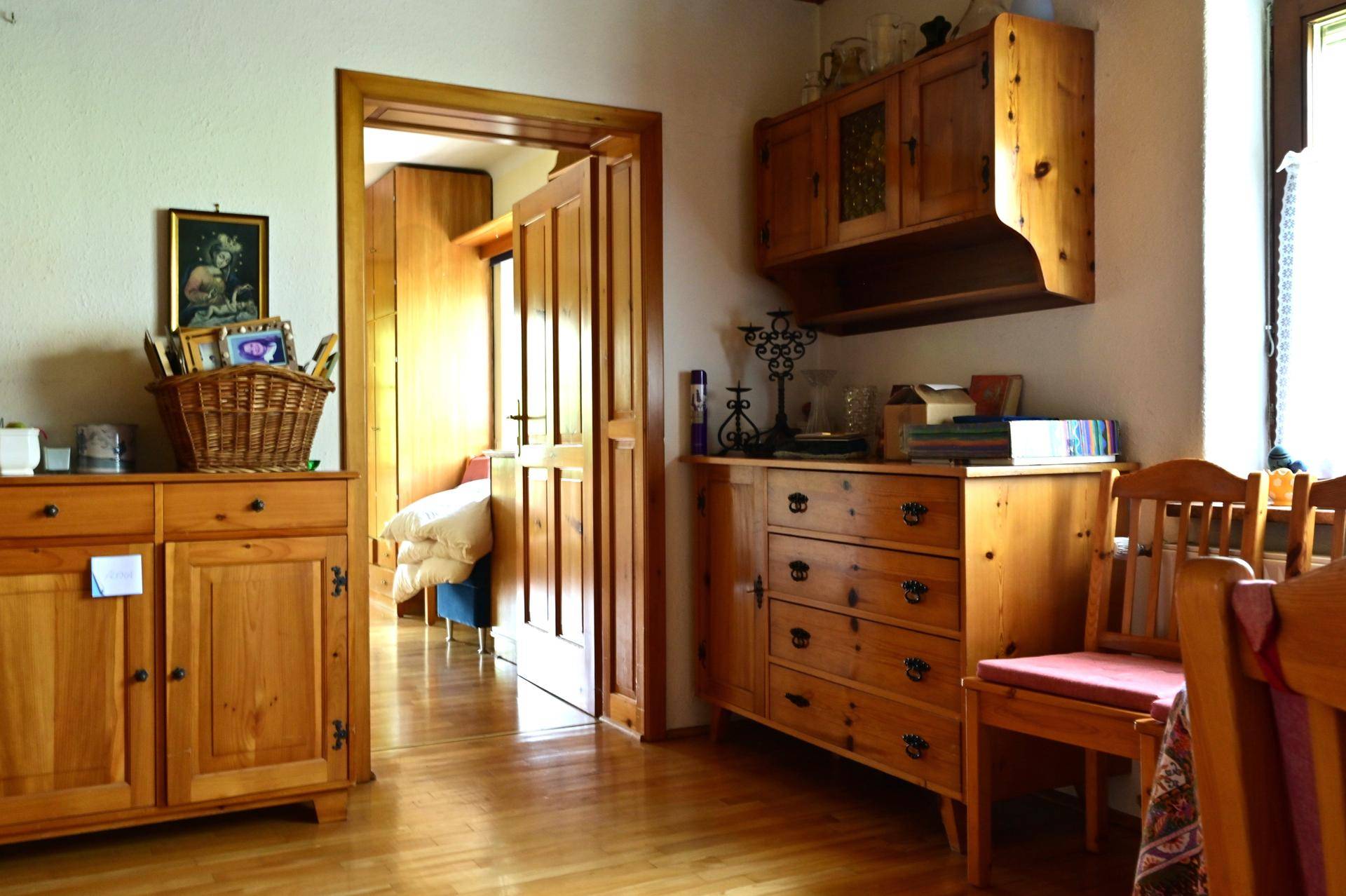 Heller Flurbereich mit rustikalen Holzmöbeln und Holzboden, führt zu weiteren Räumen.