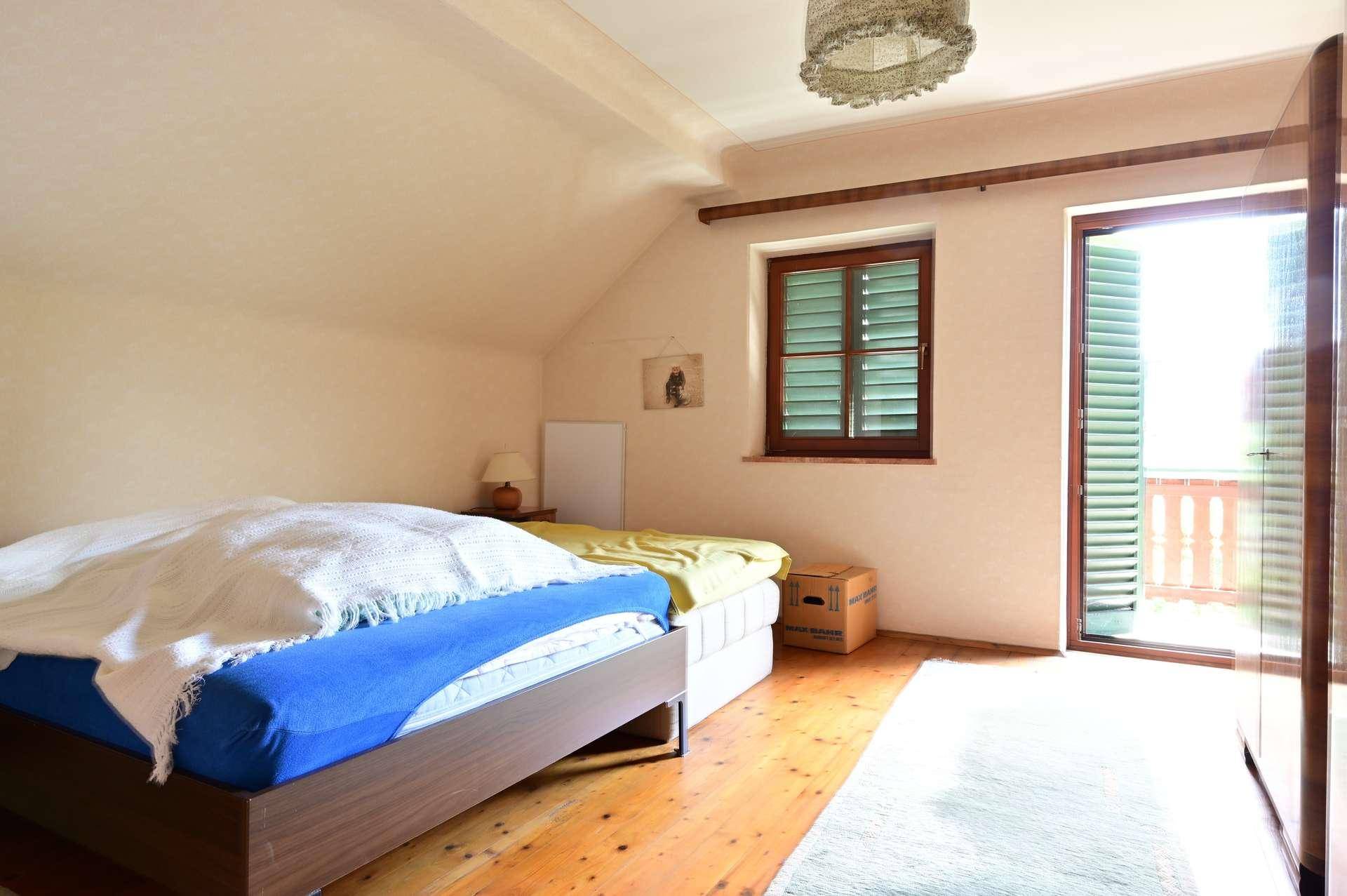Helles Schlafzimmer im Dachgeschoss mit Holzboden und Zugang zum Balkon.