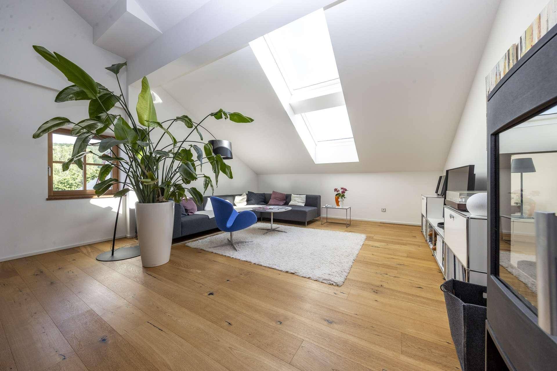 Gemütliches Wohnzimmer im Dachgeschoss mit Holzboden, Dachfenstern und viel Tageslicht.