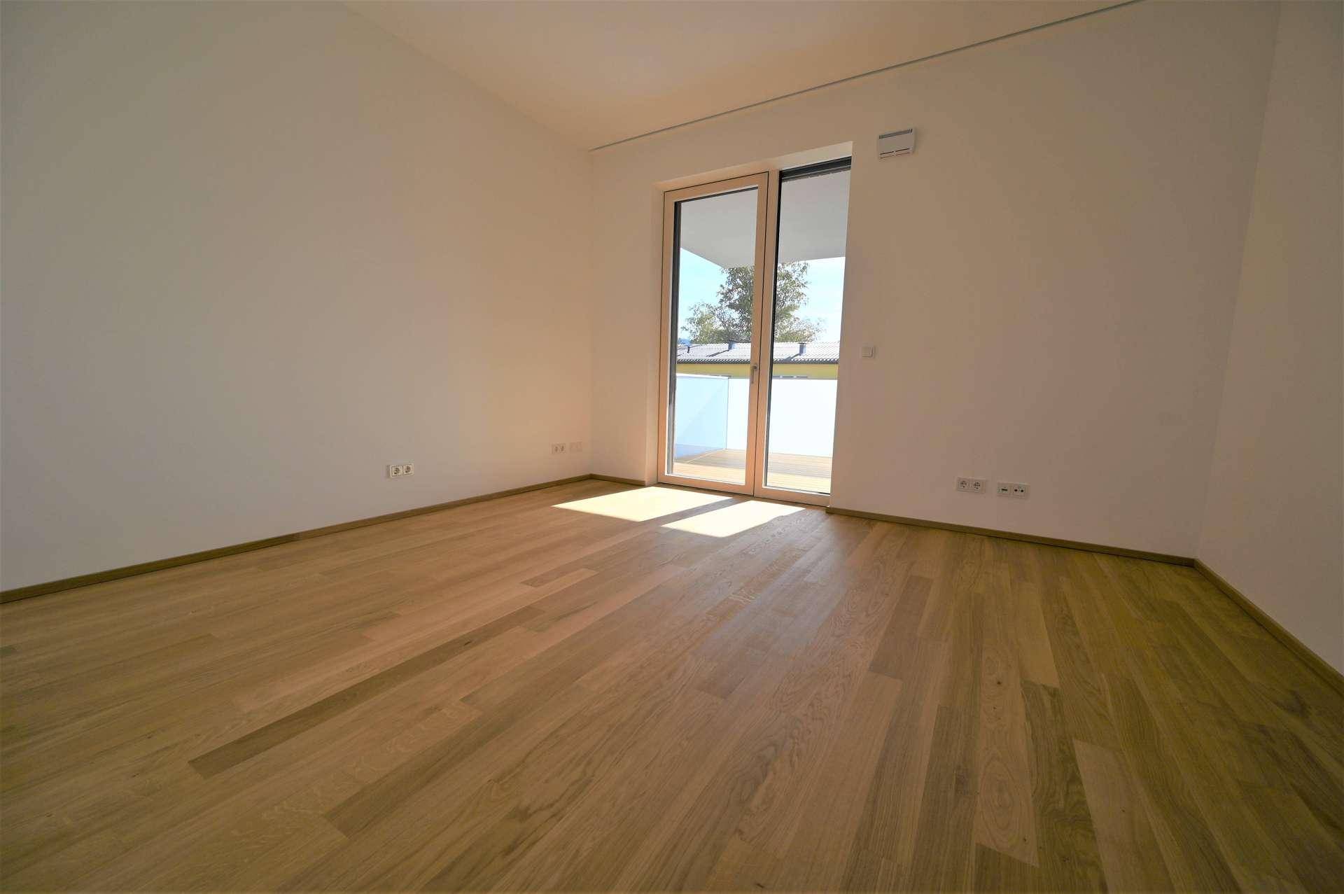 Helles Schlafzimmer mit Holzboden und Zugang zu einem Balkon oder einer Terrasse, ideal für Morgenlicht.