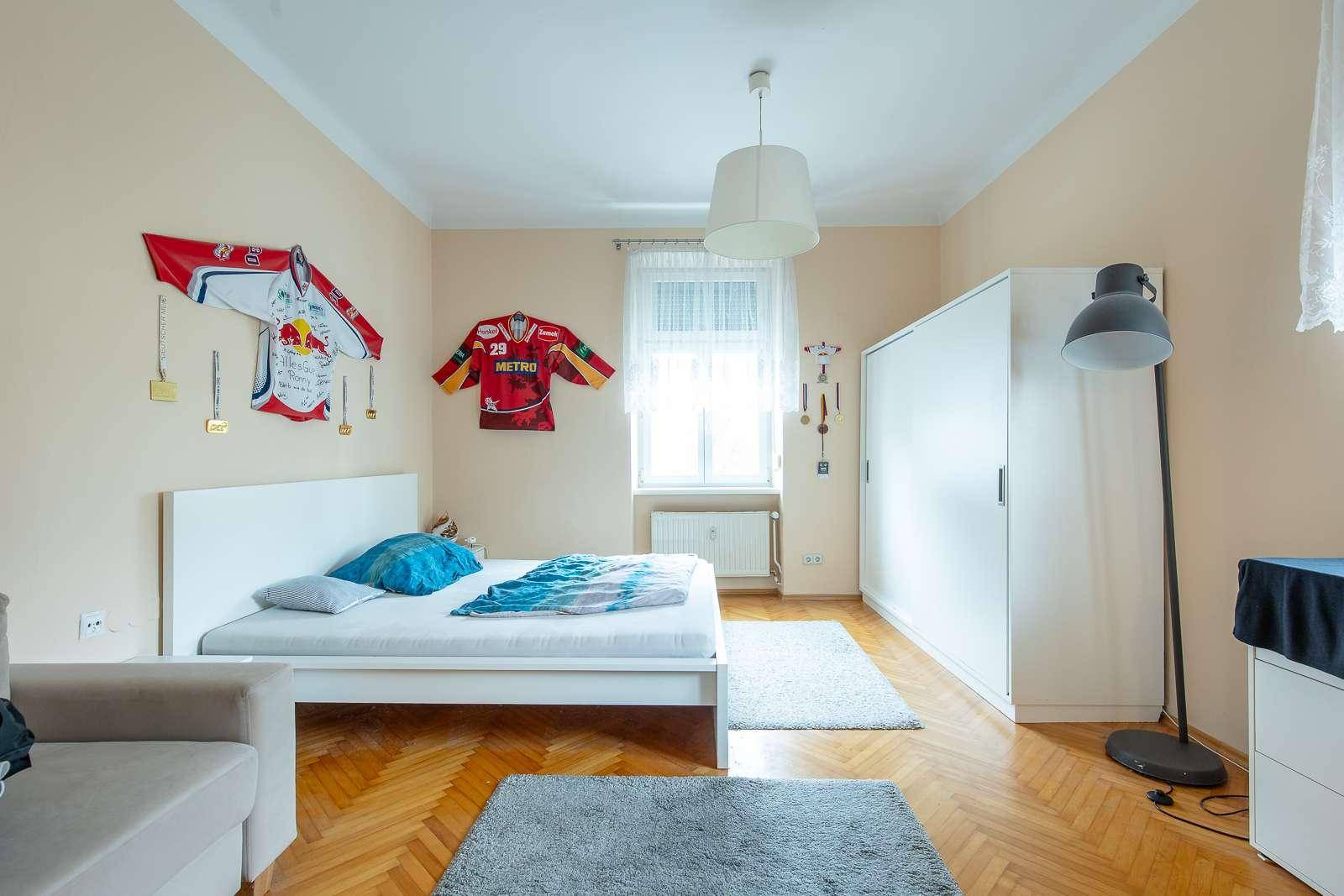 Helles Schlafzimmer mit Parkettboden, Doppelbett und großem Kleiderschrank.