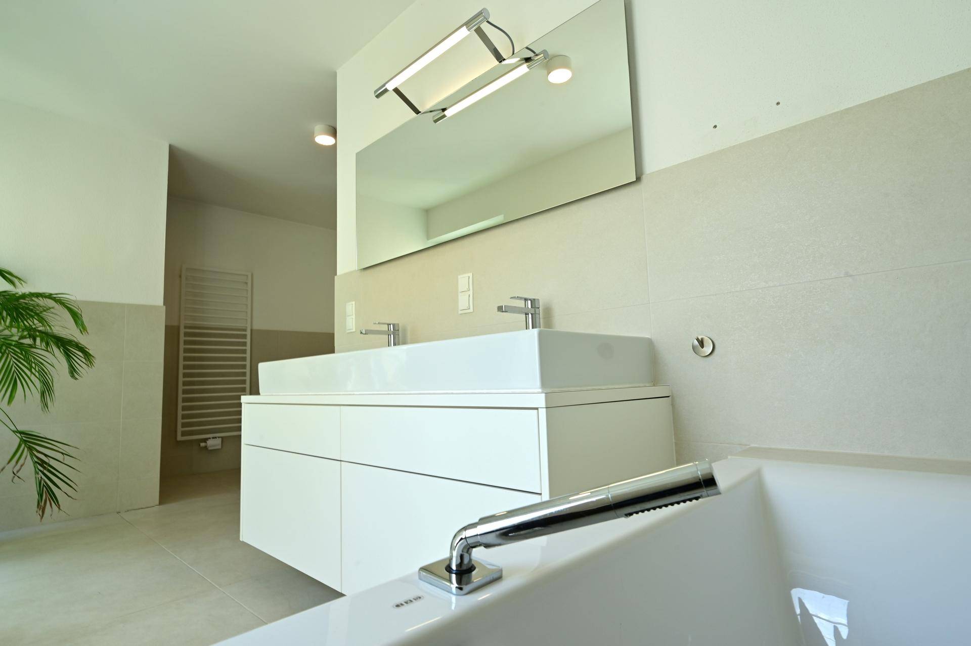 Modernes Badezimmer mit Doppelwaschbecken, großem Spiegel und einer Badewanne für Komfort und Stil.