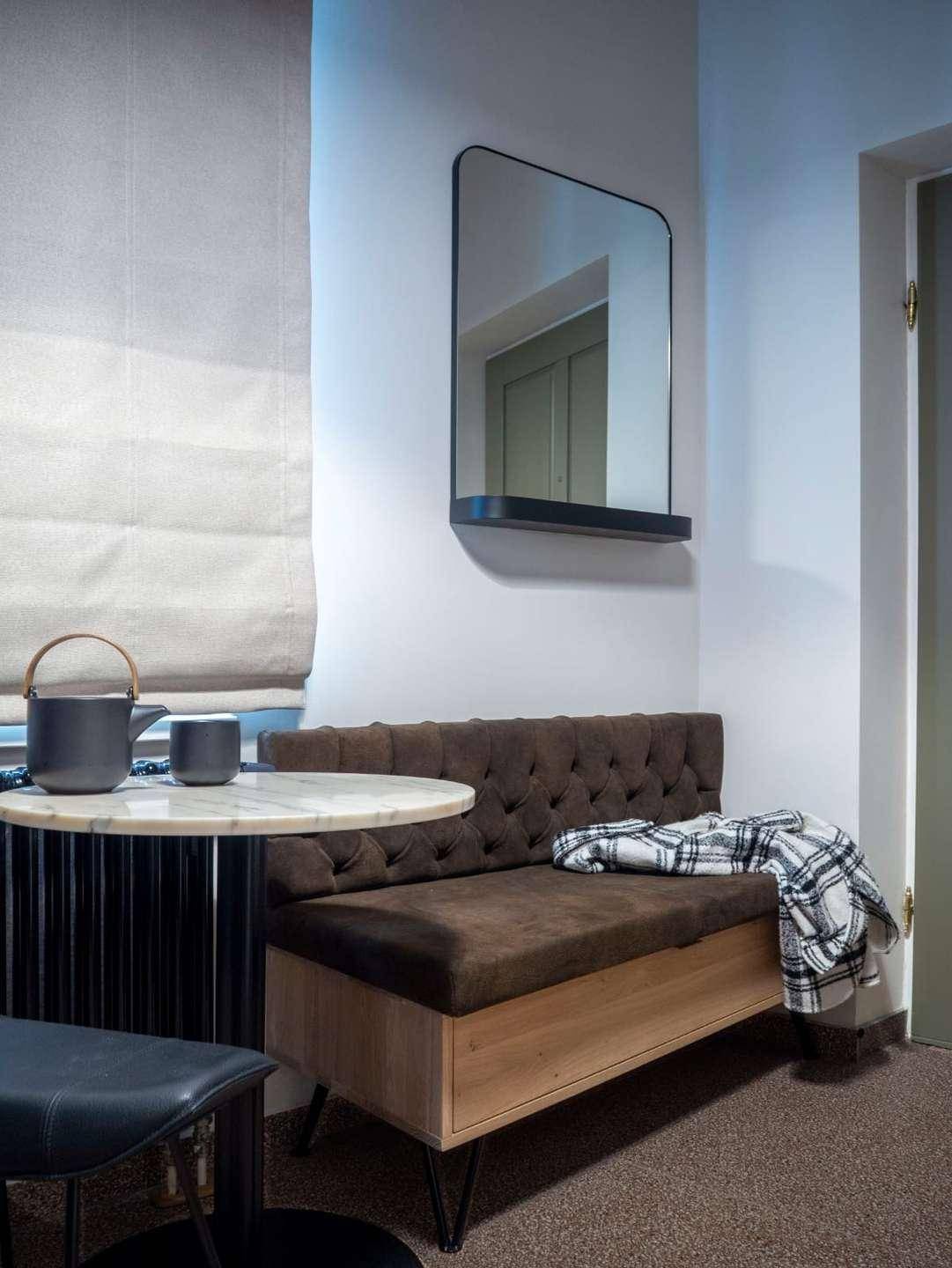 Gemütliche Sitzecke mit gepolsterter Bank, Marmortisch und Spiegel an der Wand.