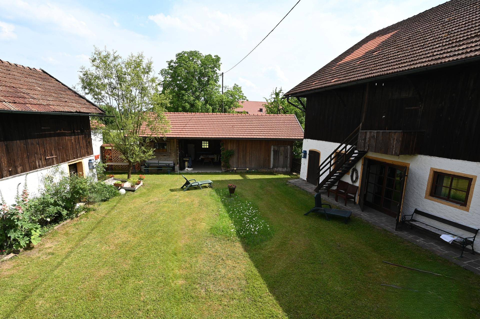 Weitläufiger Gartenbereich mit gepflegtem Rasen und traditionellen Nebengebäuden.