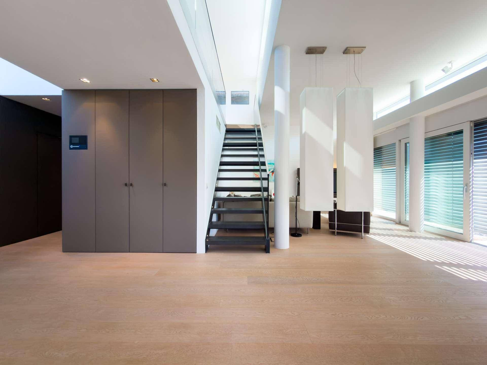 Heller Flur mit moderner Treppe, Einbauschränken und großen Fenstern für viel Licht.