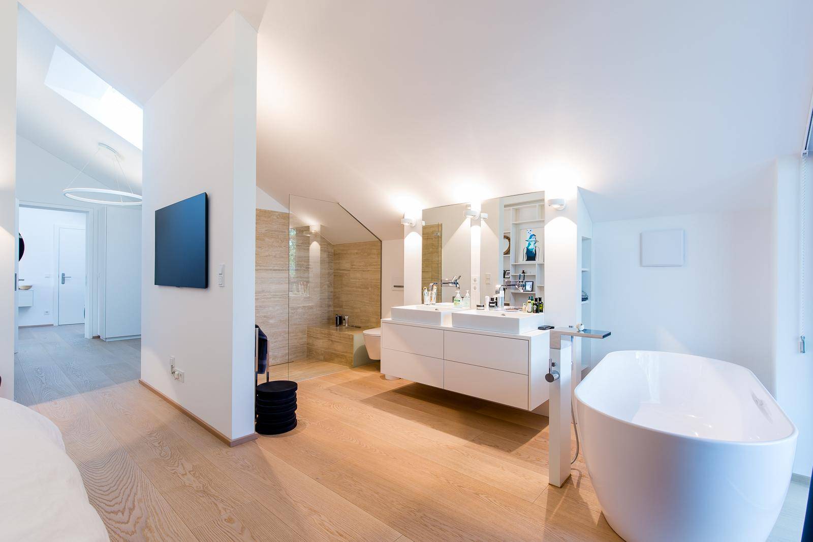 Modernes Badezimmer mit freistehender Badewanne, Doppelwaschbecken und Dachfenster für viel Licht.