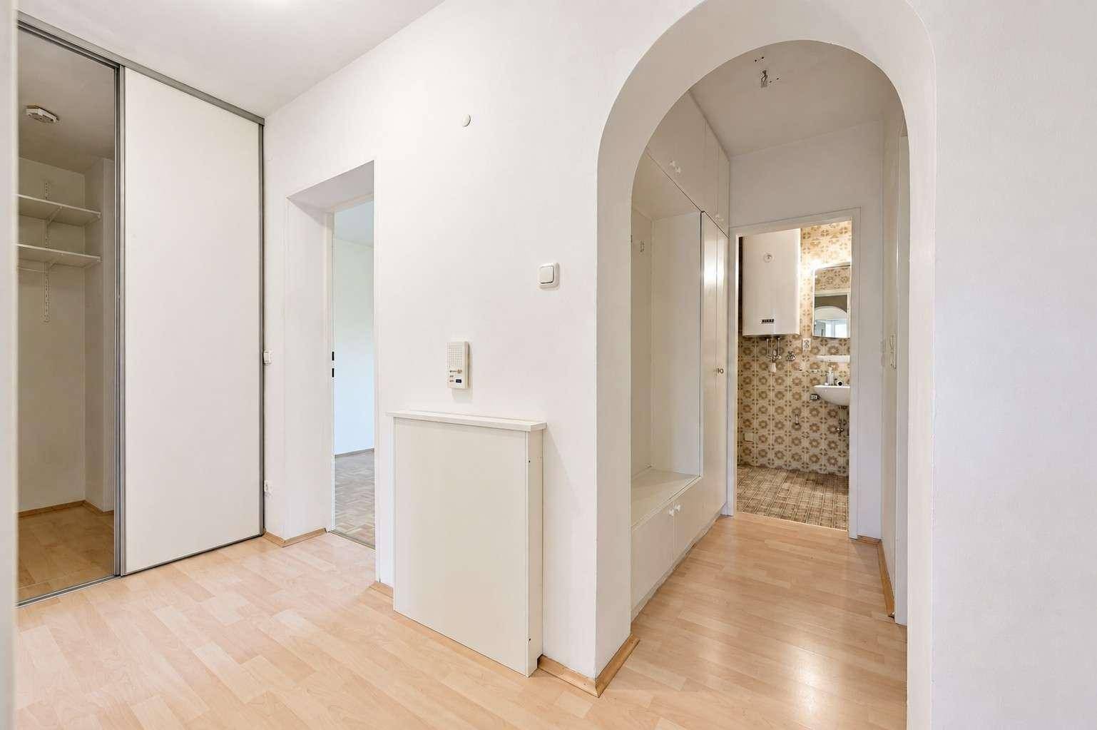 Heller Flur mit Holzboden, Einbauschrank und Blick in ein Badezimmer.