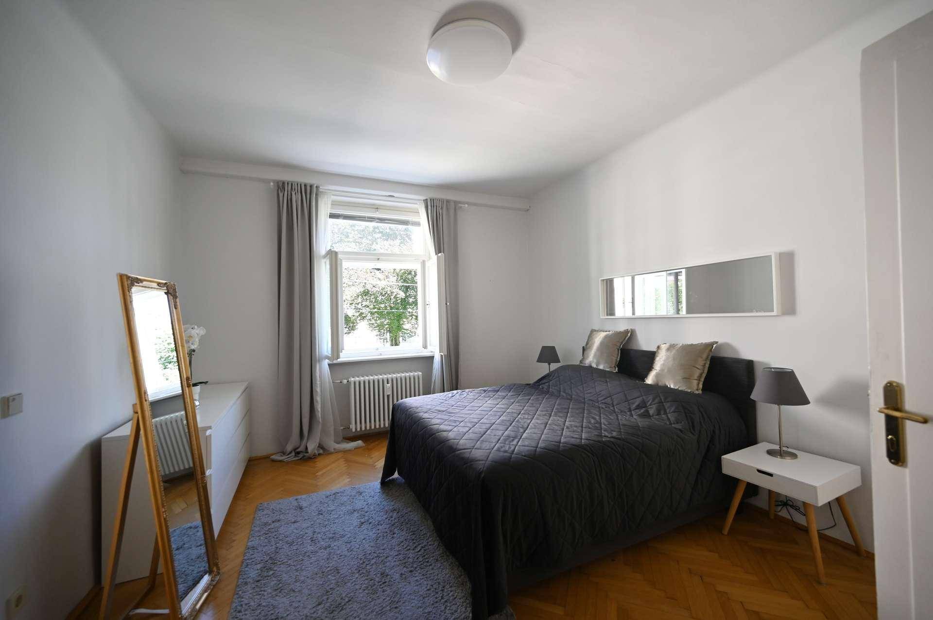 Komfortables Schlafzimmer mit großem Bett, Stehspiegel und Blick ins Grüne.