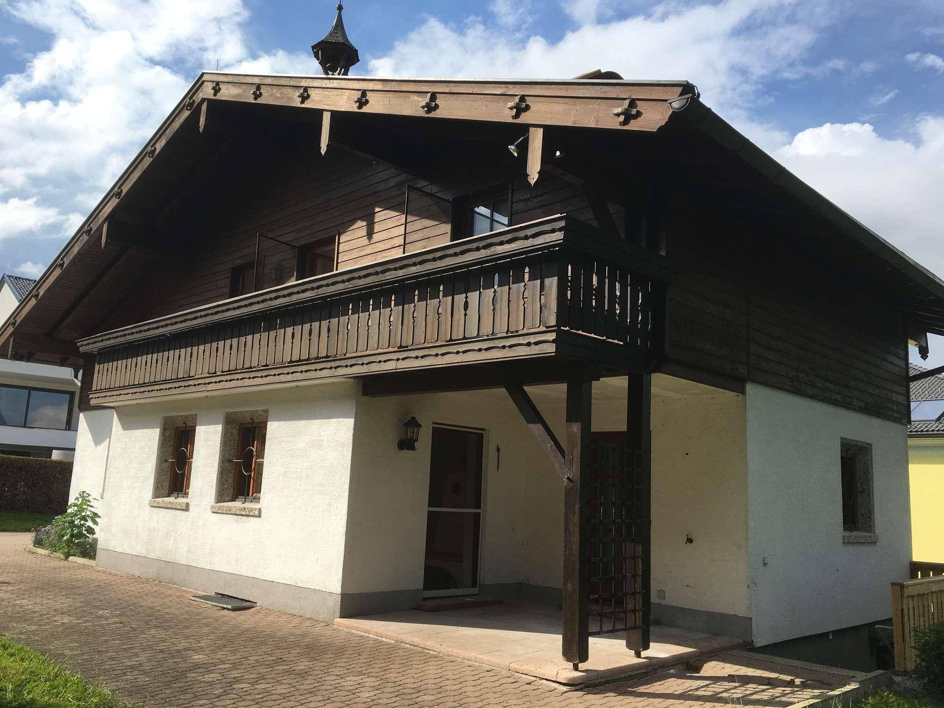 Traditionelles Haus mit weißer Fassade, Holzbalkon und Satteldach.