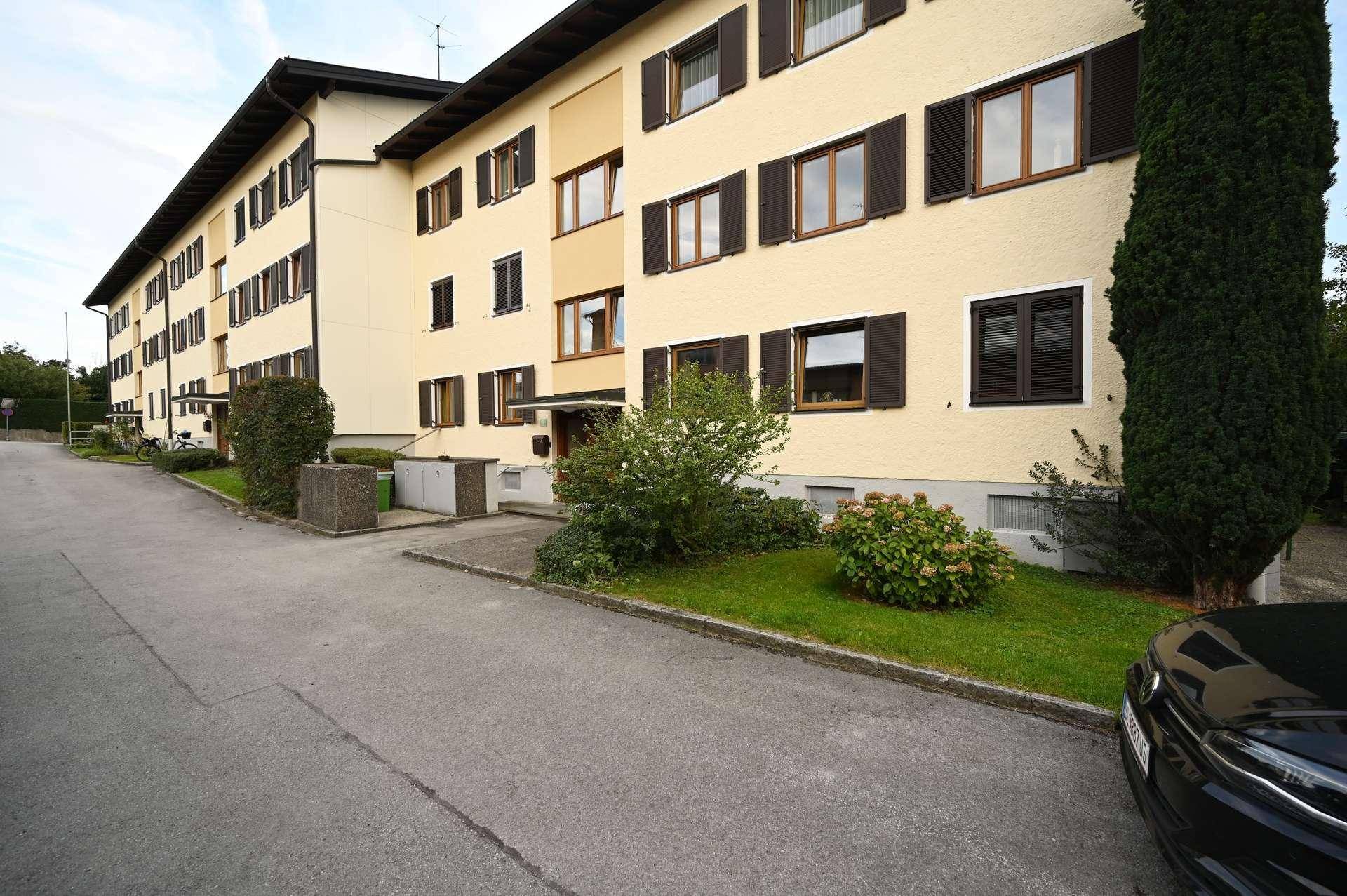 Mehrfamilienhaus mit gepflegter Fassade und Grünflächen im Vorgartenbereich.