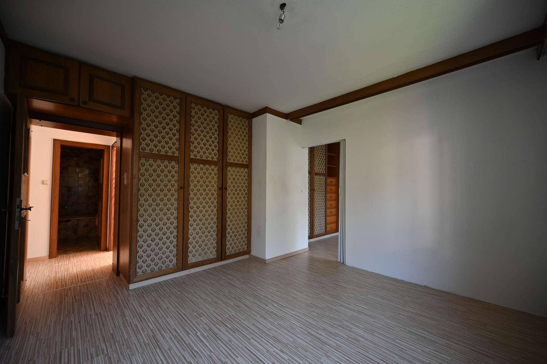 Schlafzimmer mit Holzboden und großen, gemusterten Einbauschränken.