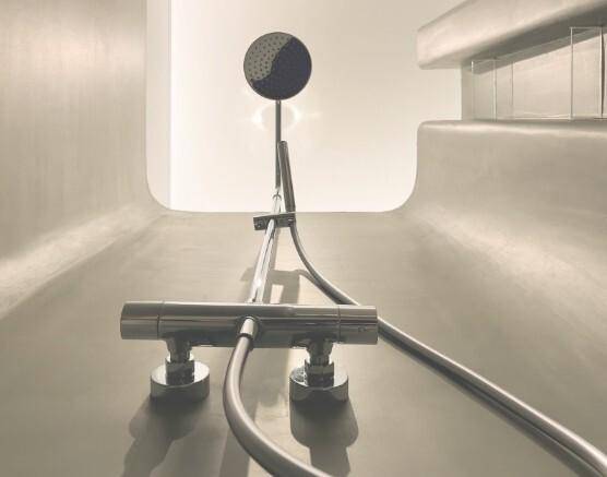 Detailaufnahme einer modernen Duscharmatur mit Regenduschkopf in einem stilvollen Badezimmer.