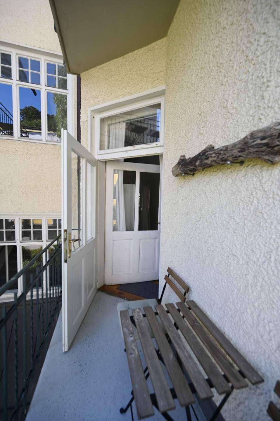 Kleiner Balkon mit Holztisch und Blick auf die umliegenden Gebäude.