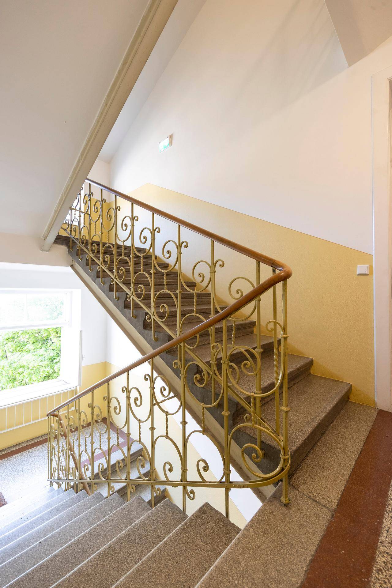 Historisches Treppenhaus mit kunstvollem schmiedeeisernem Geländer und Terrazzostufen.