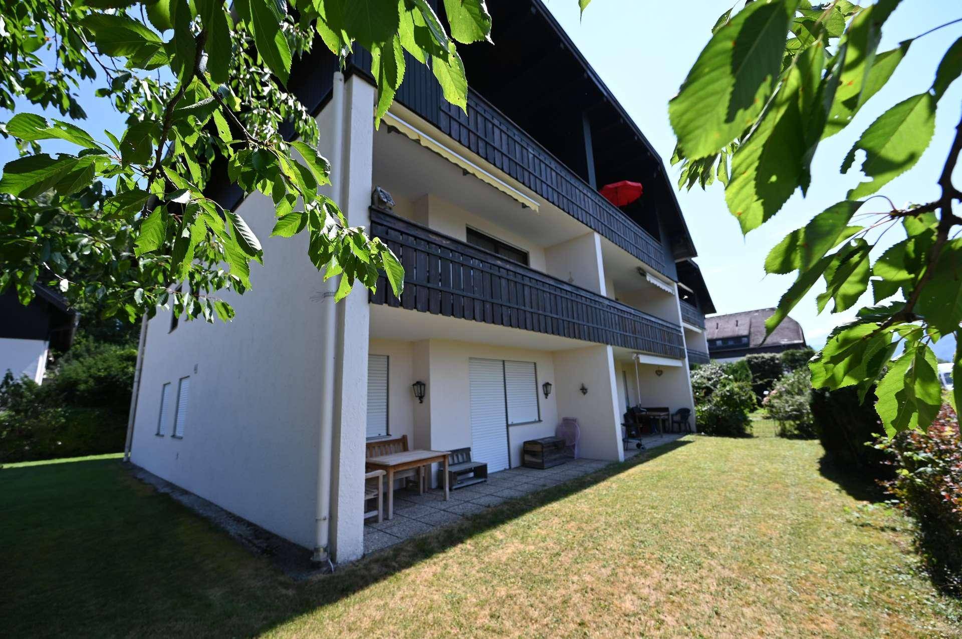 Mehrstöckiges Gebäude mit Balkonen und einem gepflegten Gartenbereich mit Sitzgelegenheiten.