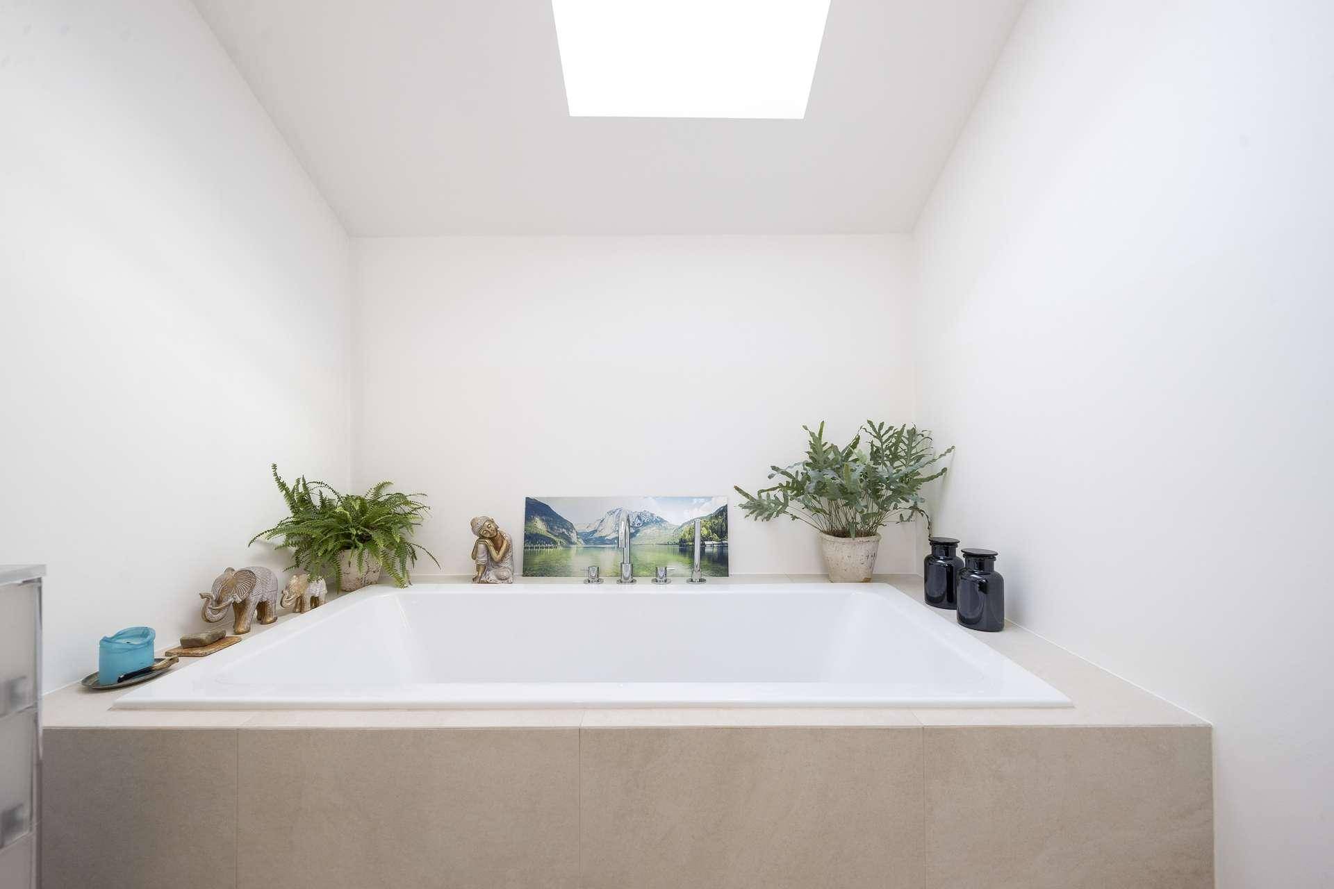 Modernes Badezimmer mit eingebauter Badewanne und einem Dachfenster für natürliches Licht.
