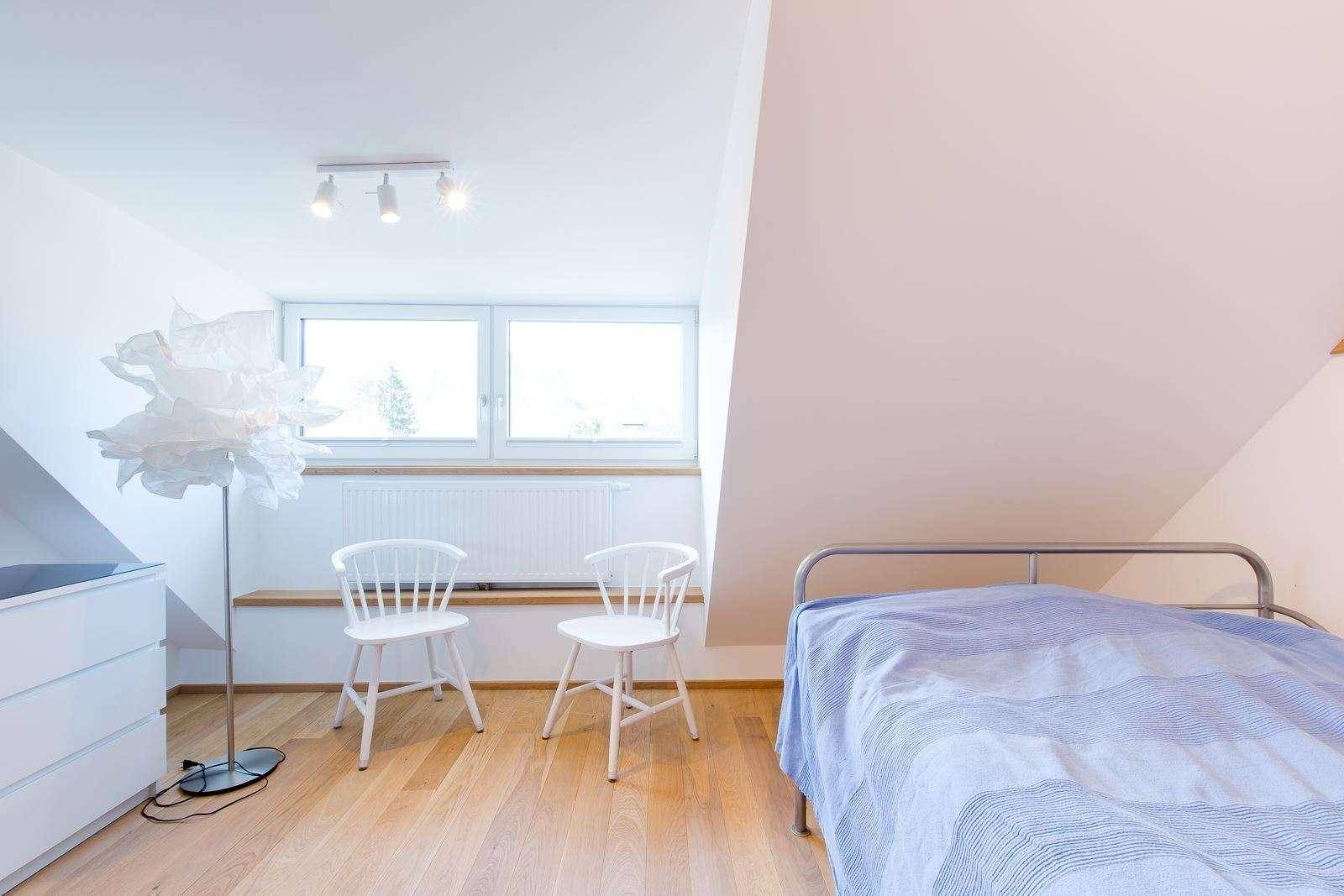 Gemütliches Schlafzimmer im Dachgeschoss mit Einzelbett, Kommode und großen Fenstern.
