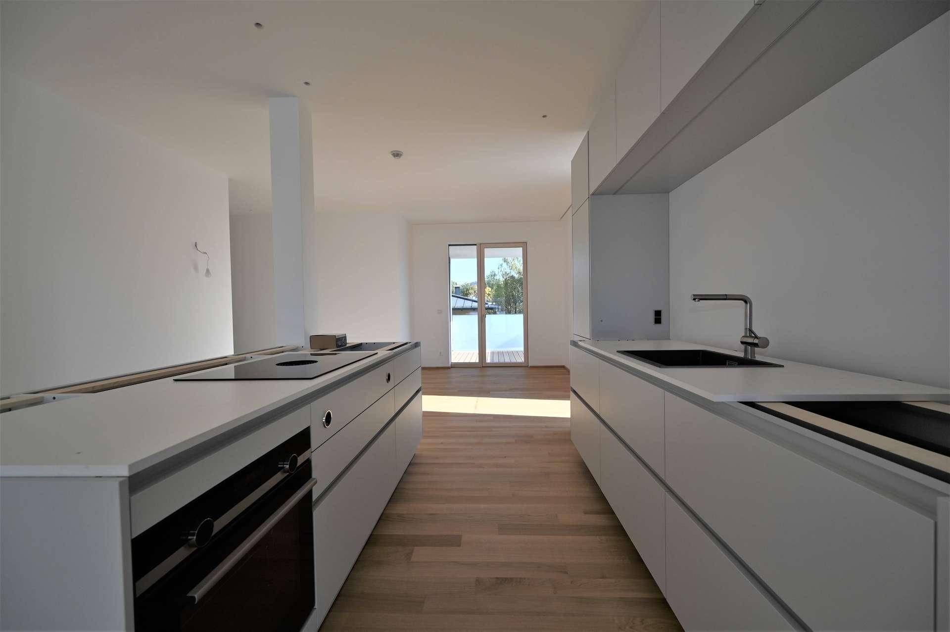 Moderne Küche mit weißen Schränken, integriertem Backofen und Induktionskochfeld, bereit zur Fertigstellung.