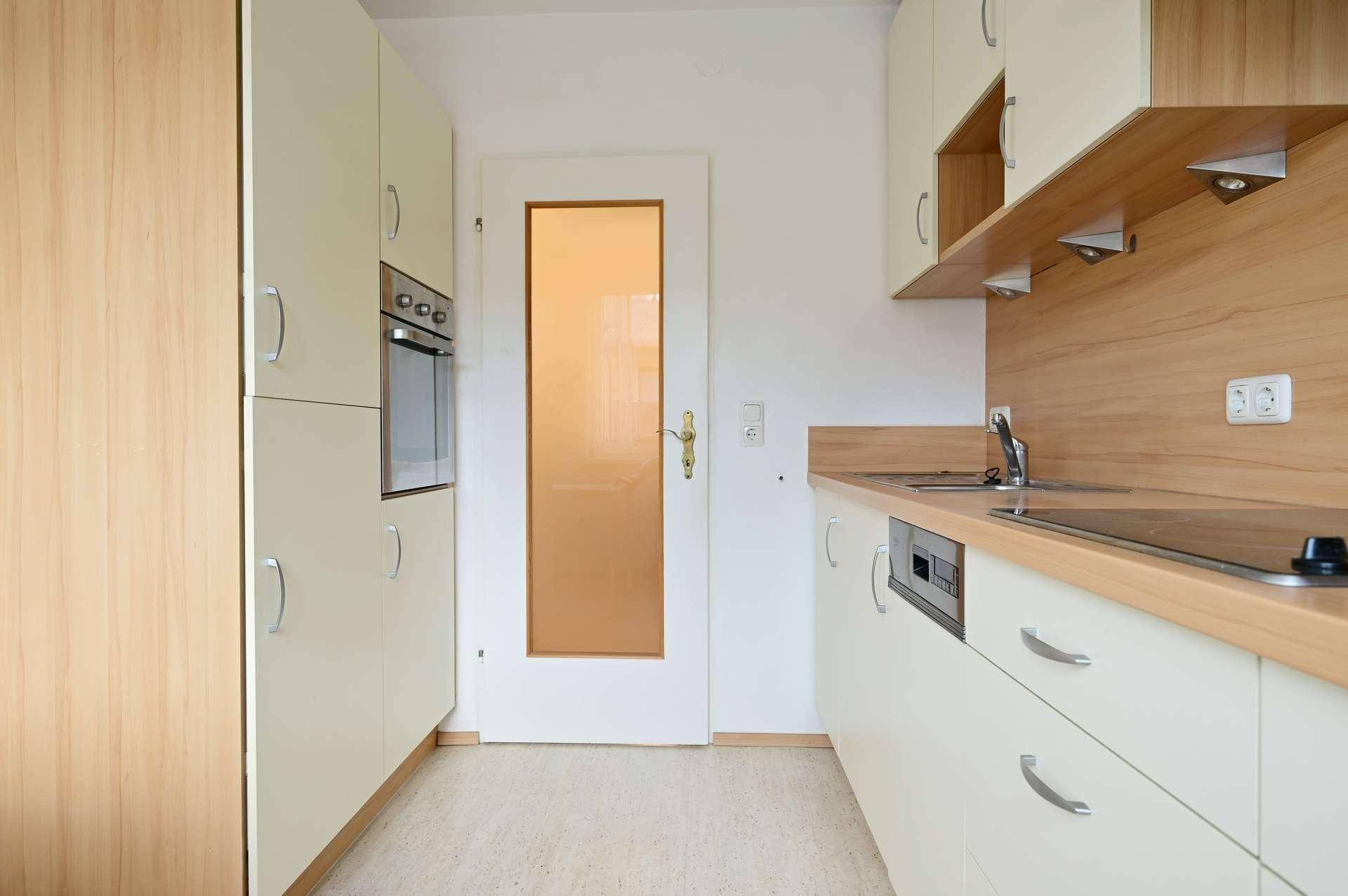 Küchenzeile mit integriertem Backofen und einer Tür mit Milchglas-Einsatz.
