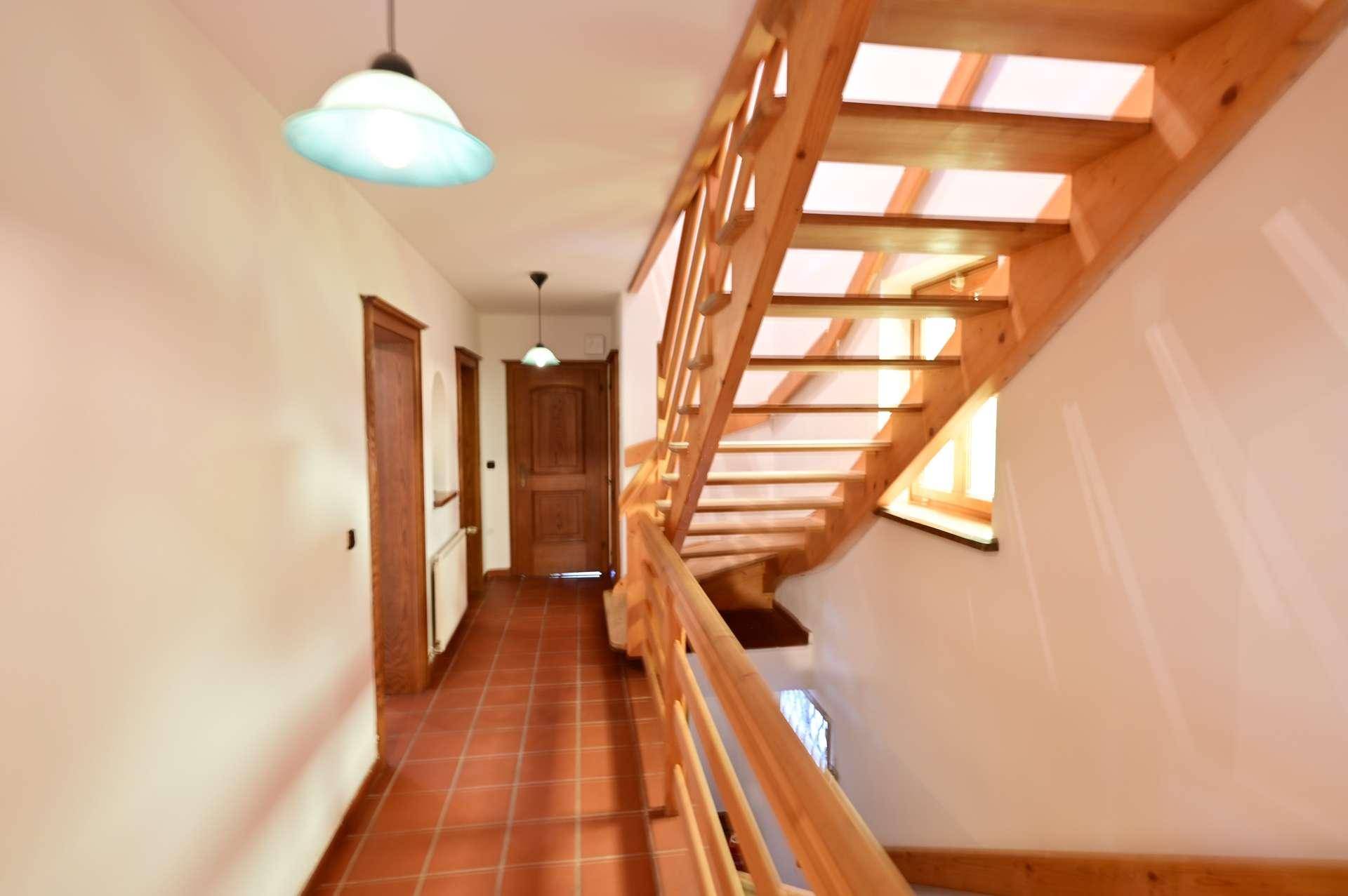 Heller Flur mit Holztreppe, Terrakottafliesen und traditionellen Holztüren.