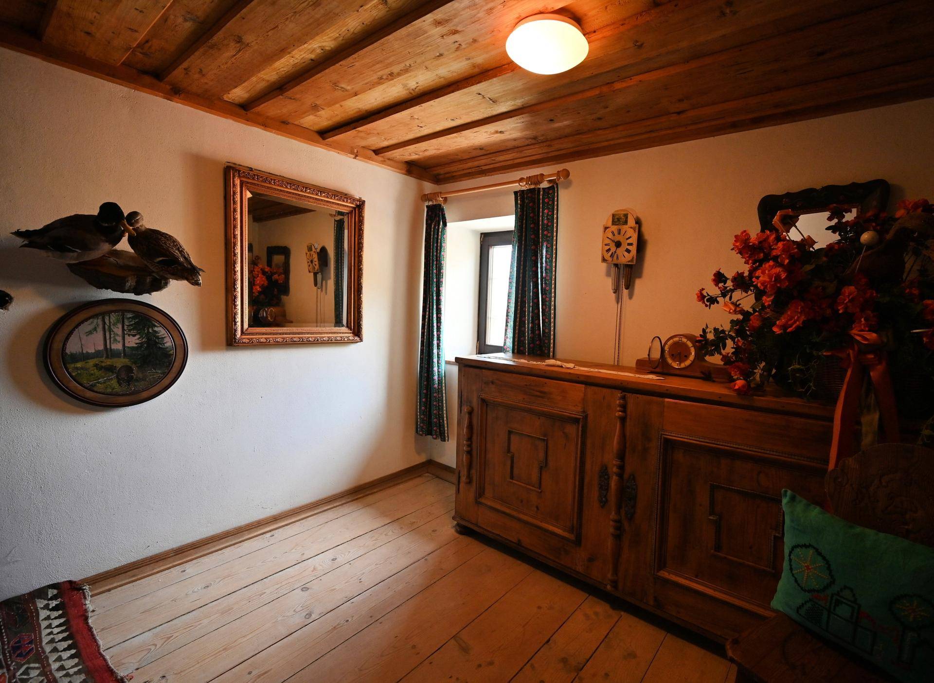 Raum mit Holzbalkendecke, Dielenboden und traditionellen Holzmöbeln.