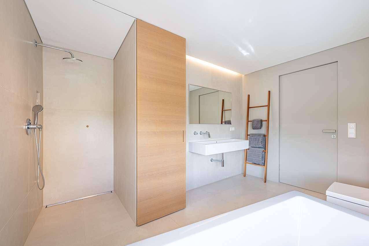 Modernes Badezimmer mit begehbarer Dusche, elegantem Waschbecken und indirekter Beleuchtung.