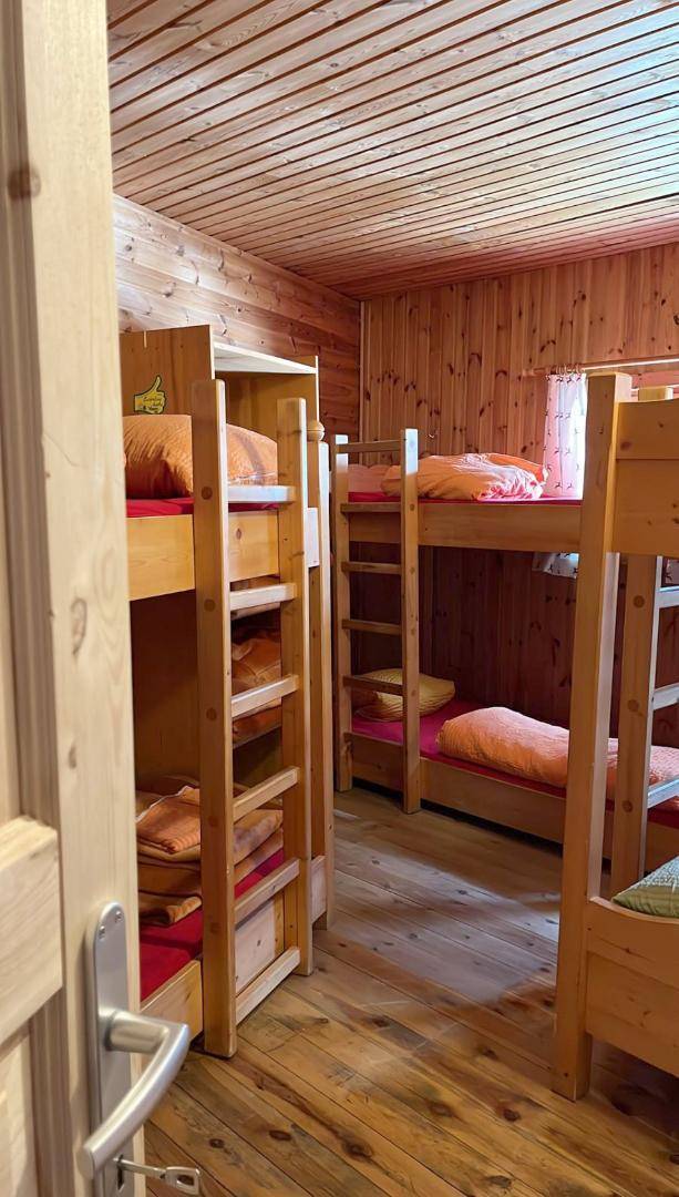 Schlafsaal mit mehreren Etagenbetten und Holzausstattung, ideal für Gruppenunterkünfte in einer Hütte.