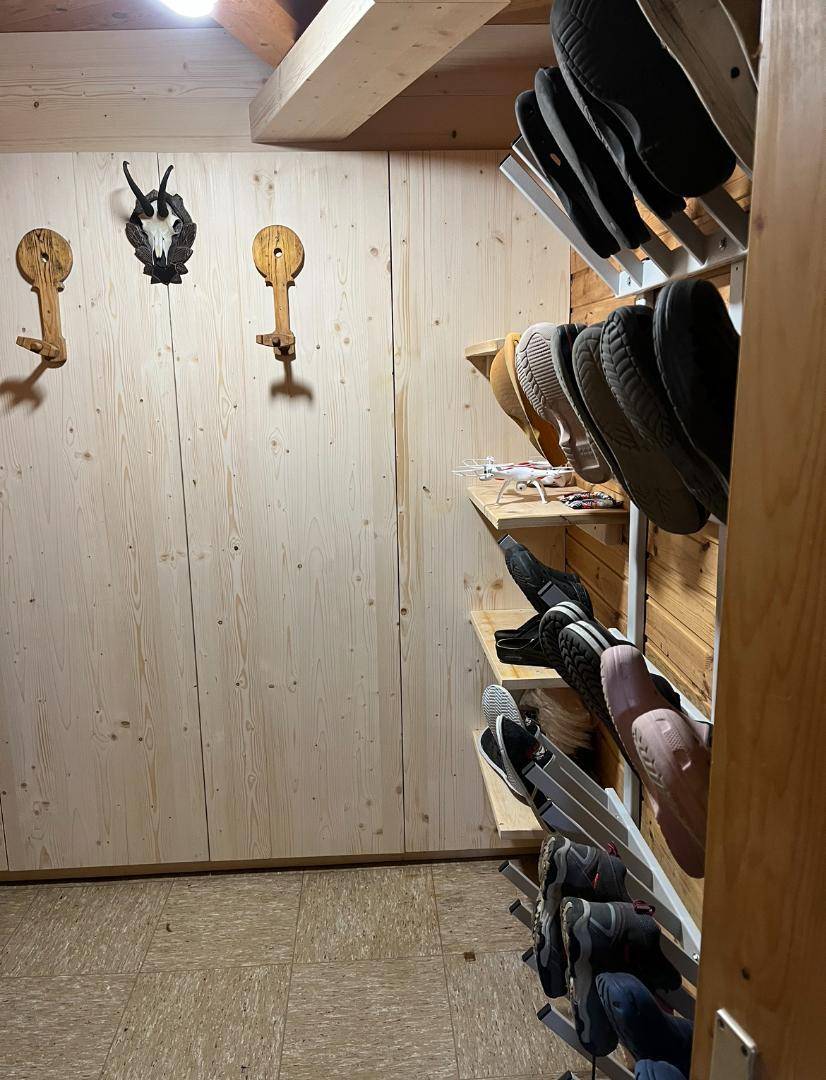 Einfacher Schuhraum mit Holzverkleidung und Regalen zur Aufbewahrung von Schuhen.