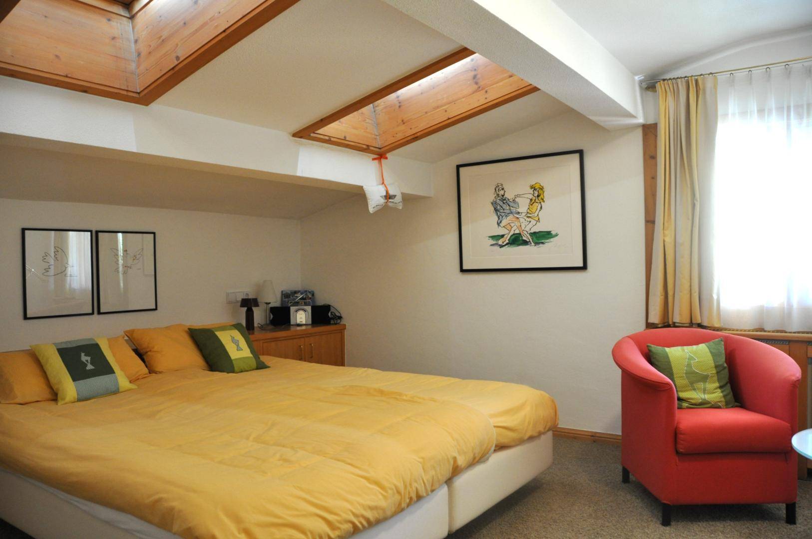 Schlafzimmer mit Doppelbett, Dachschrägen und zwei Dachfenstern für natürliches Licht.
