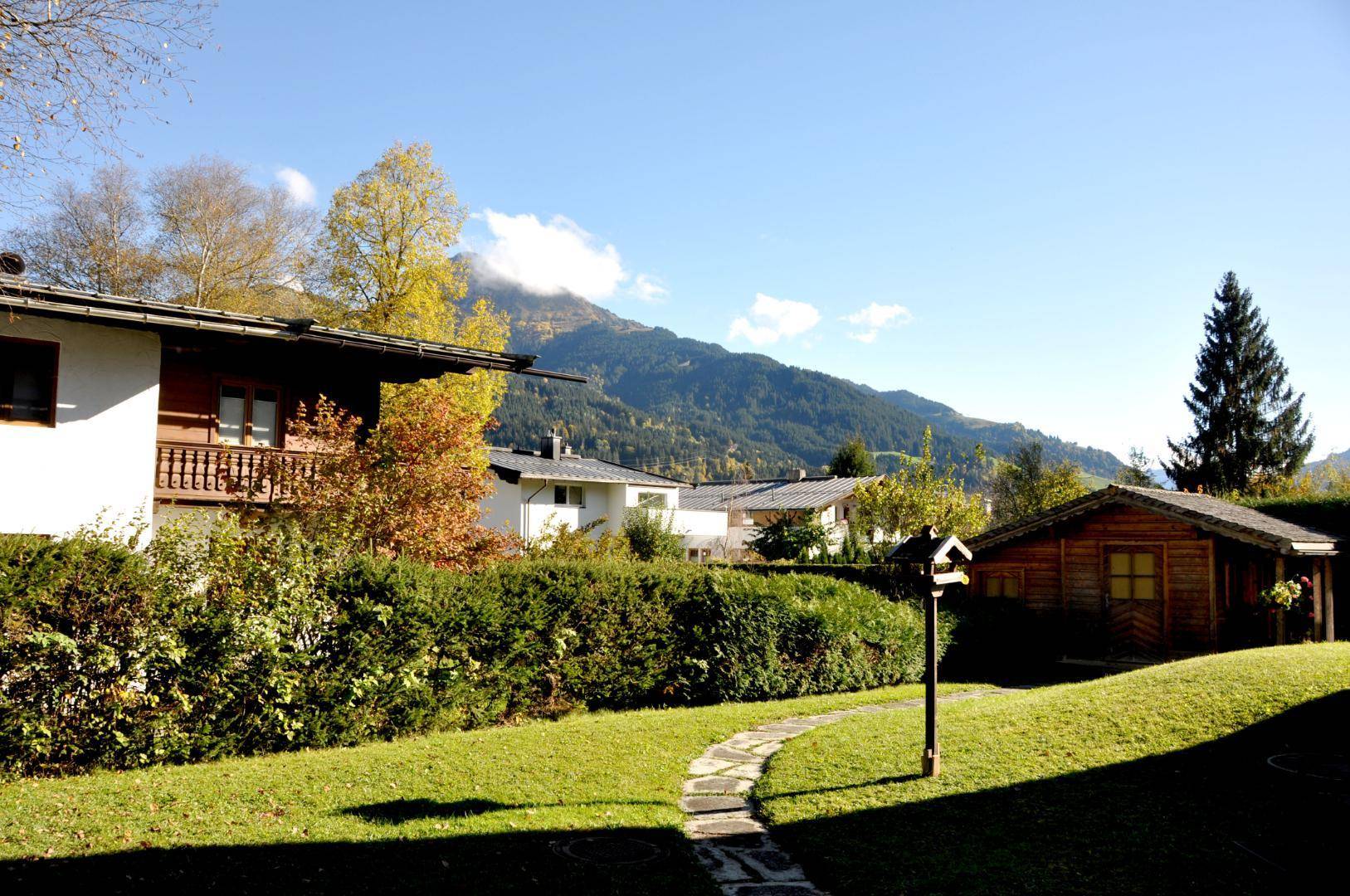 Gepflegter Garten mit Steinweg, Gartenhaus und Bergblick im Hintergrund.