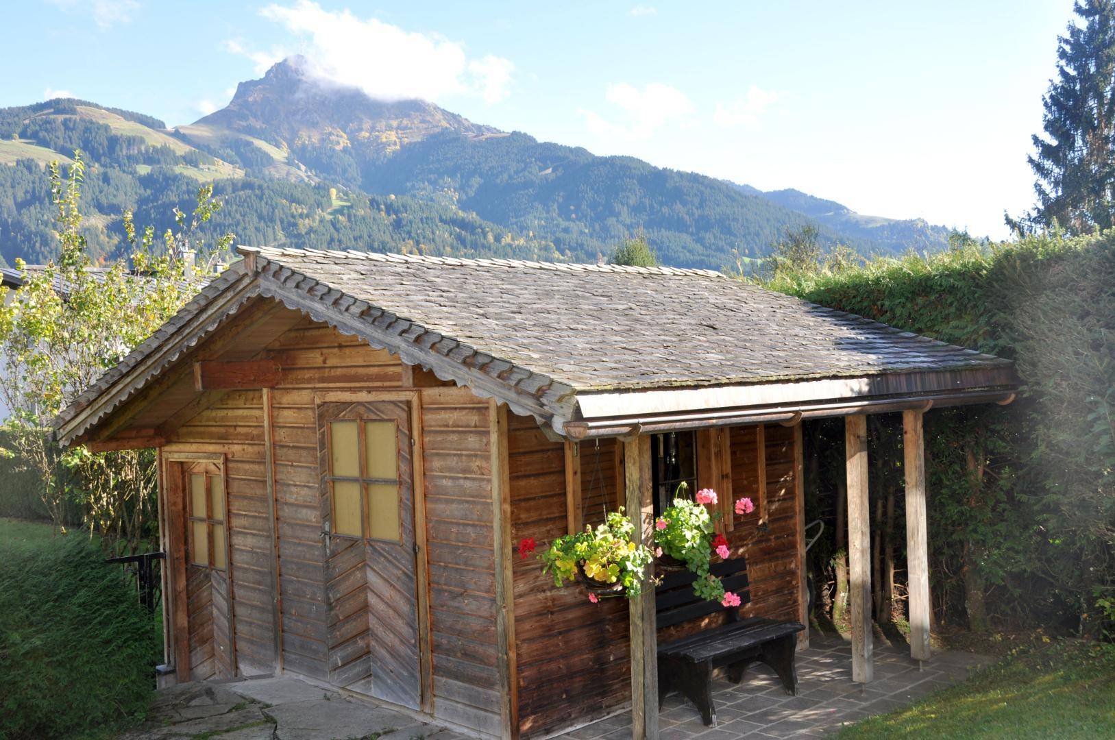 Rustikales Gartenhaus aus Holz mit kleiner Veranda und Blumenkästen.
