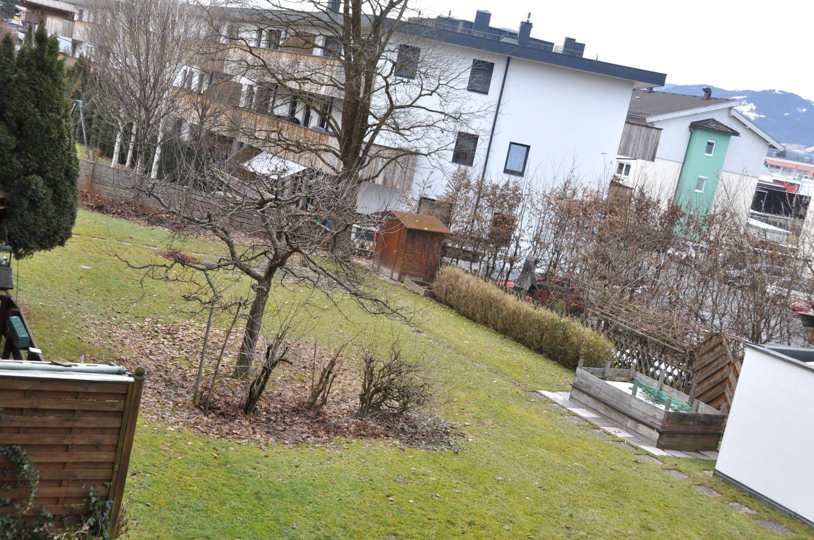 Großer, gepflegter Gartenbereich mit Rasenfläche, Bäumen und einem kleinen Gartenhaus.