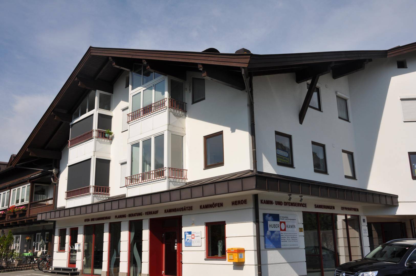Fassade eines modernen Gebäudes mit großen Fenstern und traditionellen Holzelementen.