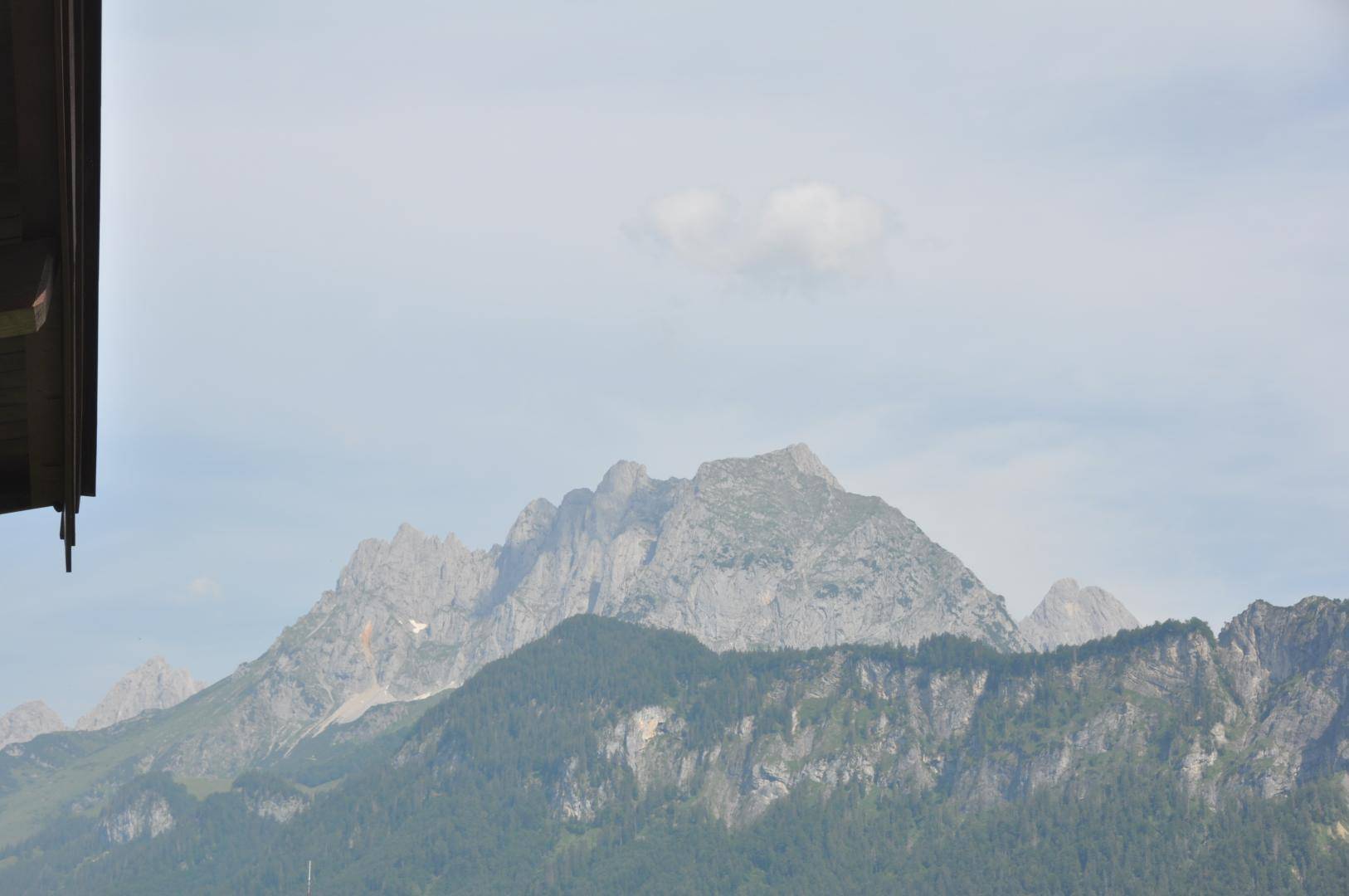 Majestätischer Bergblick mit felsigen Gipfeln und bewaldeten Hängen unter blauem Himmel.