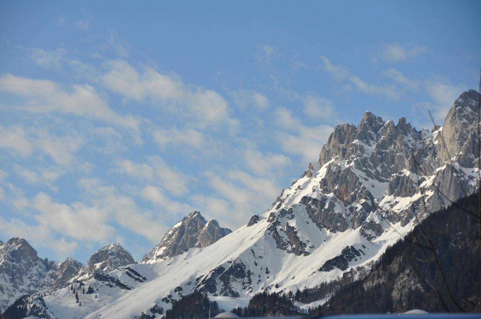 Beeindruckender Blick auf schneebedeckte Berggipfel unter einem teilweise bewölkten Himmel.