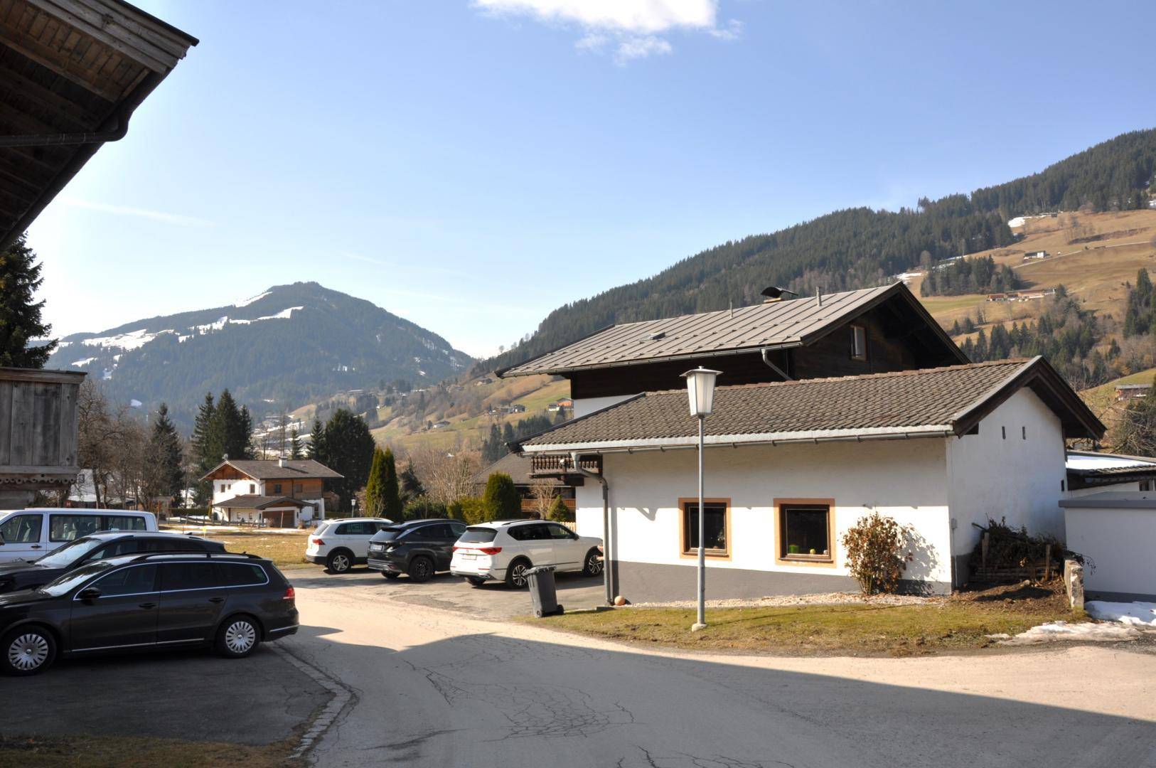 Blick auf die Straße mit Häusern, geparkten Autos und den umliegenden Bergen.