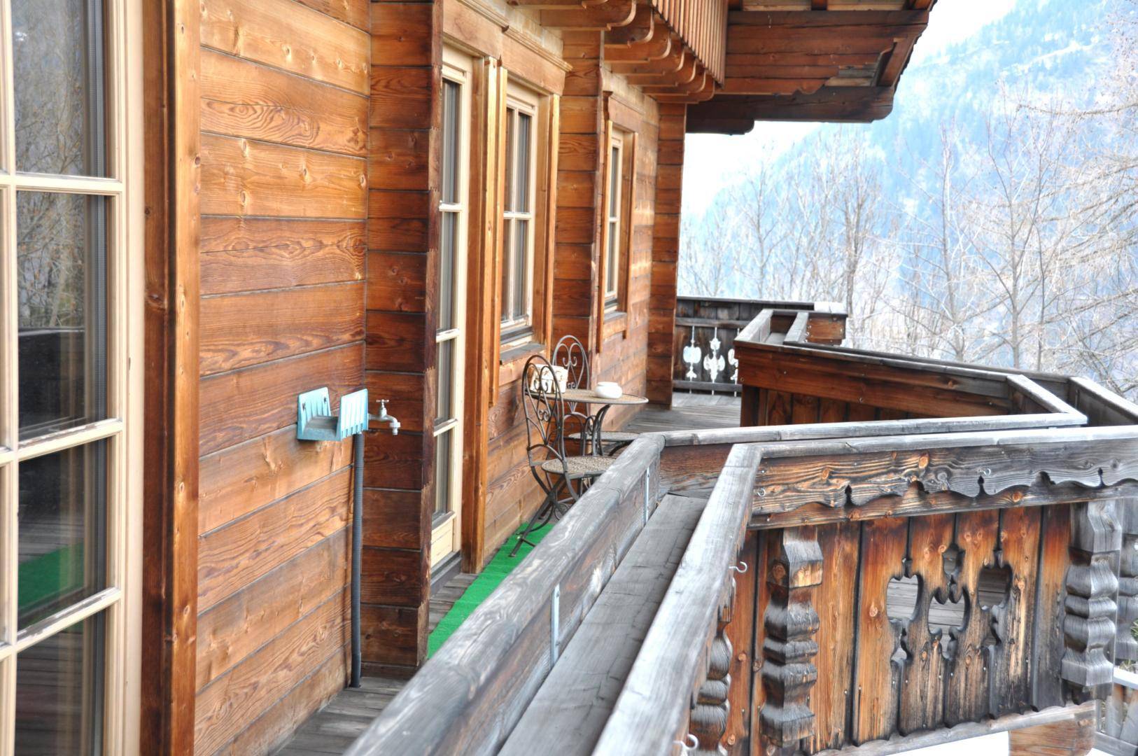 Traditioneller Holzbalkon mit Sitzgelegenheiten und weitem Blick auf die umliegende Berglandschaft.