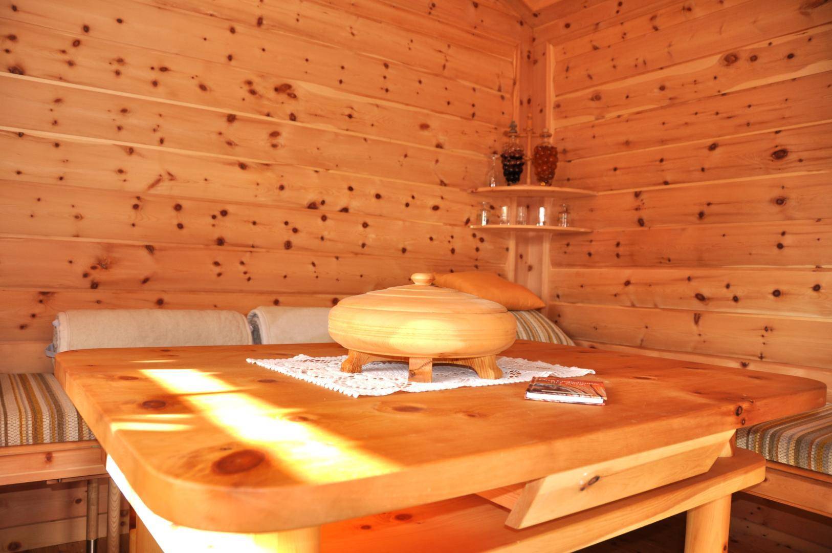 Gemütlicher Essbereich mit Holztisch und Bänken, umgeben von rustikalen Holzvertäfelungen.