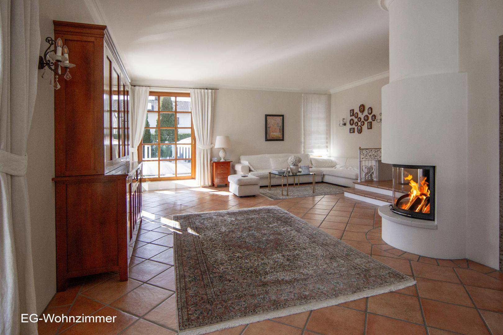 Helles Wohnzimmer mit Terrakotta-Fliesenboden, modernem Kamin und traditionellen Möbeln.