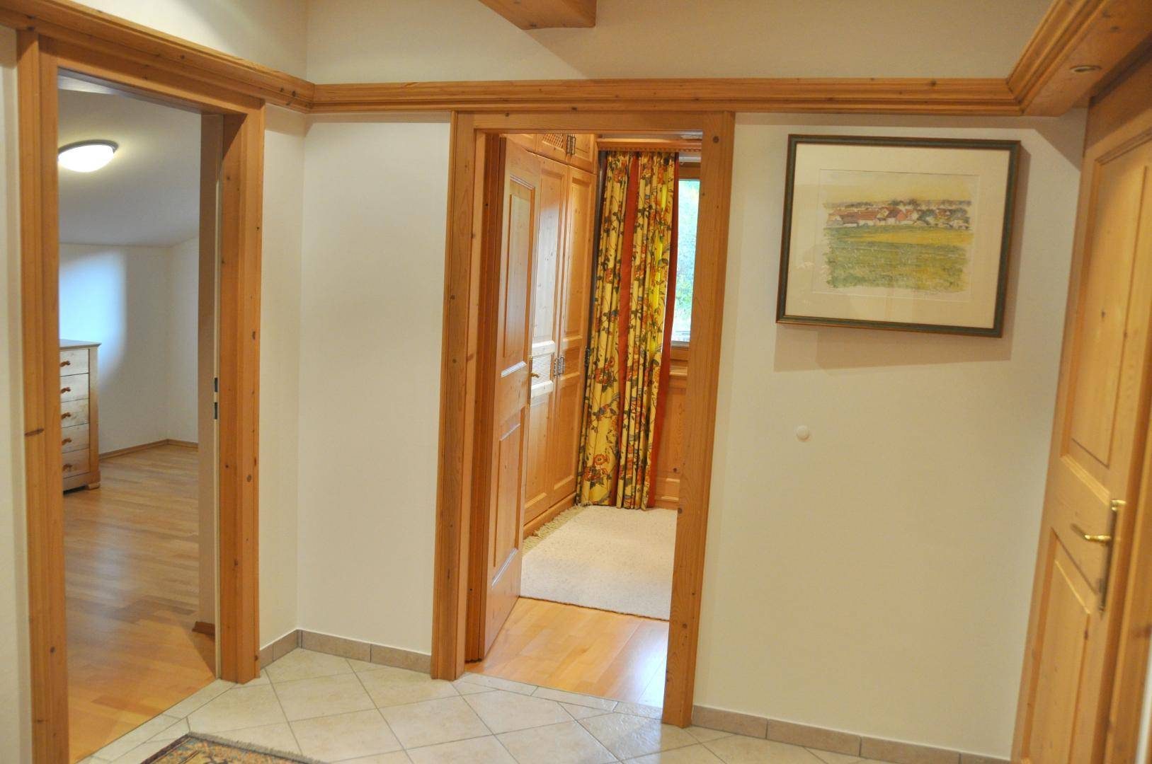 Heller Flur mit Fliesenboden und Holztürrahmen, der zu angrenzenden Schlafzimmern führt.