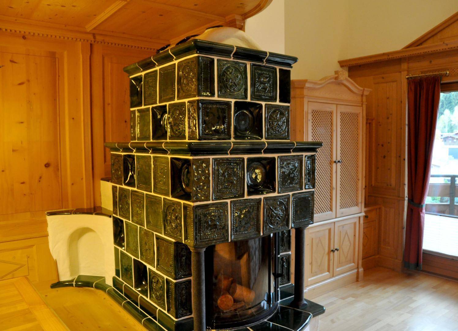 Detailansicht des großen, kunstvollen grünen Kachelofens mit traditionellen Fliesenmustern.