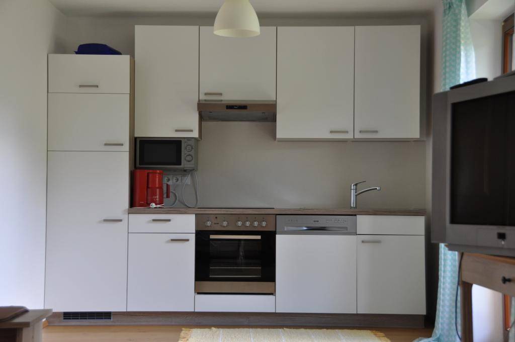 Funktionale Einbauküche mit weißen Schränken, integriertem Backofen, Mikrowelle und Spülmaschine.
