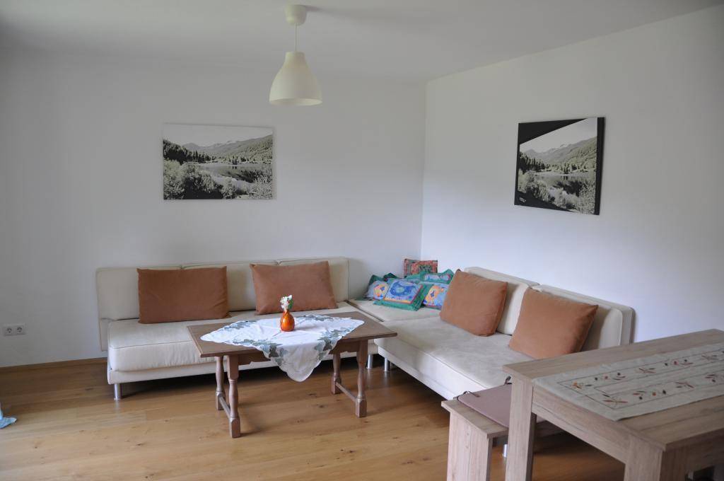 Gemütlicher Wohnbereich mit beigen Sofas, einem Holztisch und Bildern an den weißen Wänden.