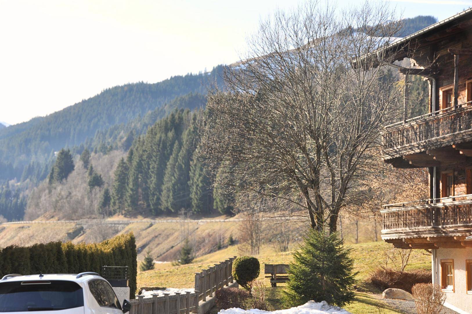 Traditionelles Holzhaus mit mehreren Balkonen und Blick auf bewaldete Hügel.