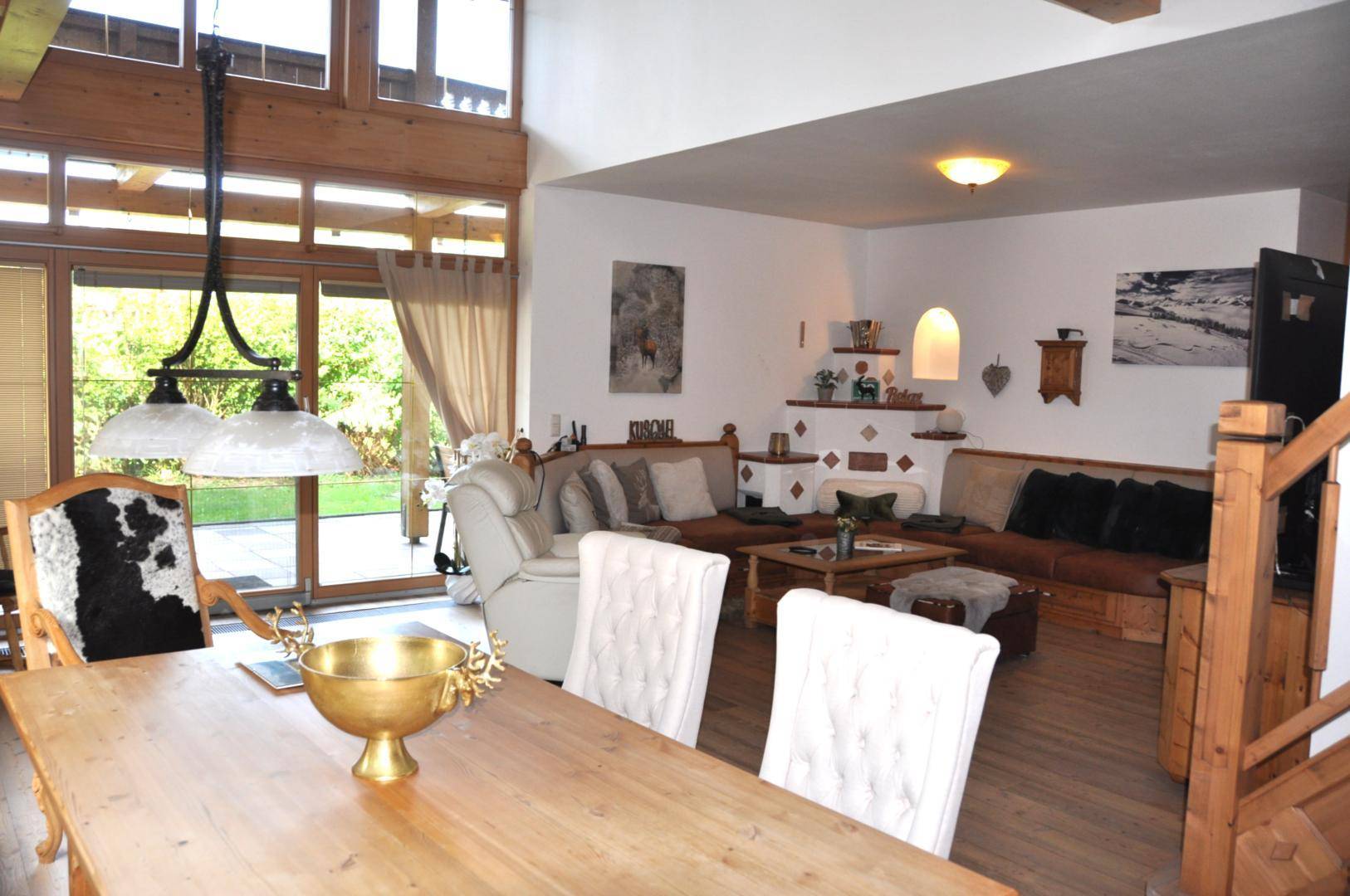 Geräumiger Wohn- und Essbereich mit hohen Decken, Holzbalken und Zugang zum Garten.