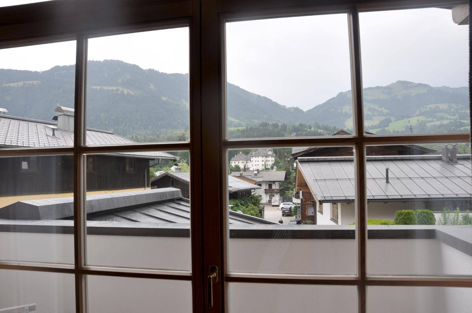 Fensterblick auf die umliegende Berglandschaft und traditionelle Häuser.