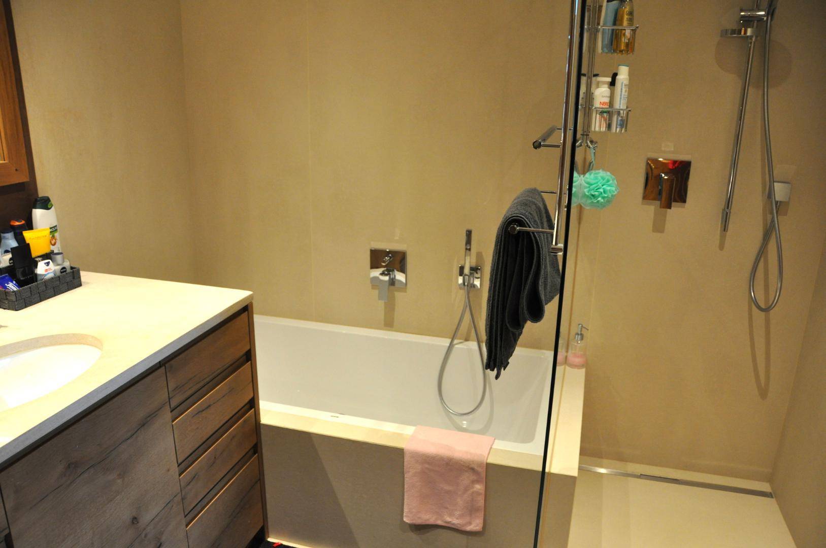 Modernes Badezimmer mit Badewanne, Duschbereich und beigefarbenen Wänden.