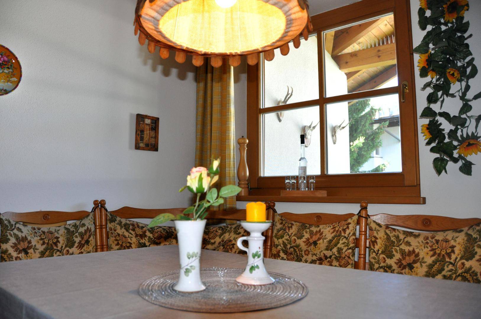 Detailansicht des Essbereichs mit Holztisch, traditionellen Stühlen und Fensterdekoration.