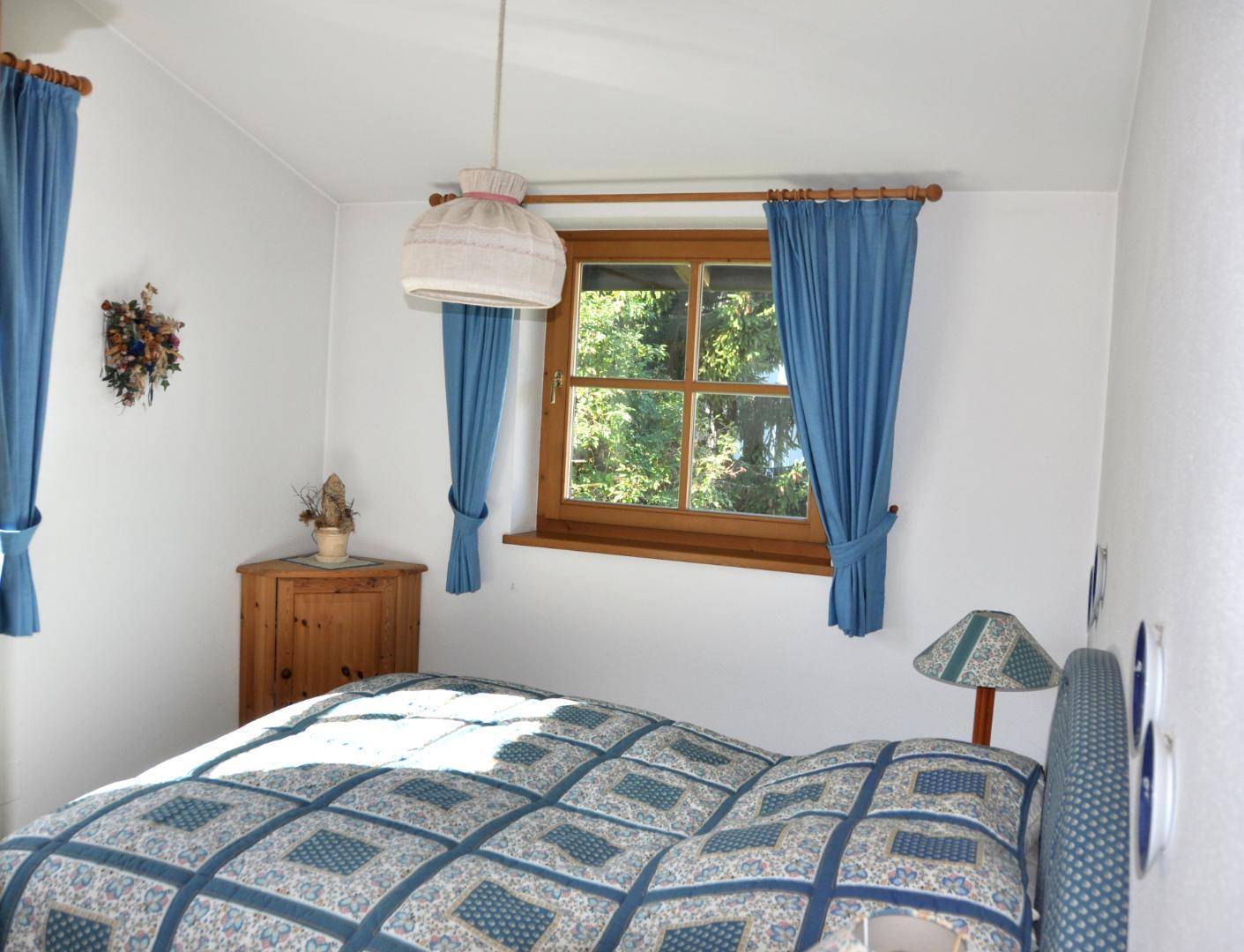 Gemütliches Schlafzimmer mit Doppelbett, blauer Bettwäsche und einem hölzernen Nachttisch.