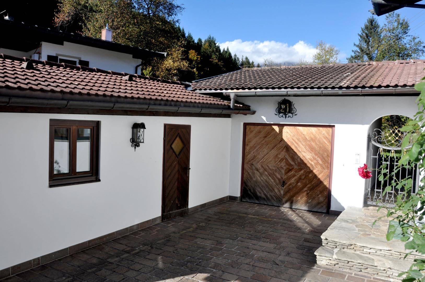 Einfahrt mit Garagentor aus Holz und gepflastertem Bereich vor dem Hauseingang.